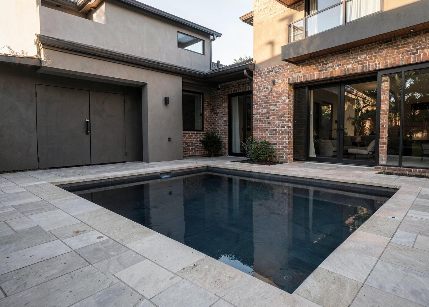 New rectangular pool with stone deck beside a modern Houston home